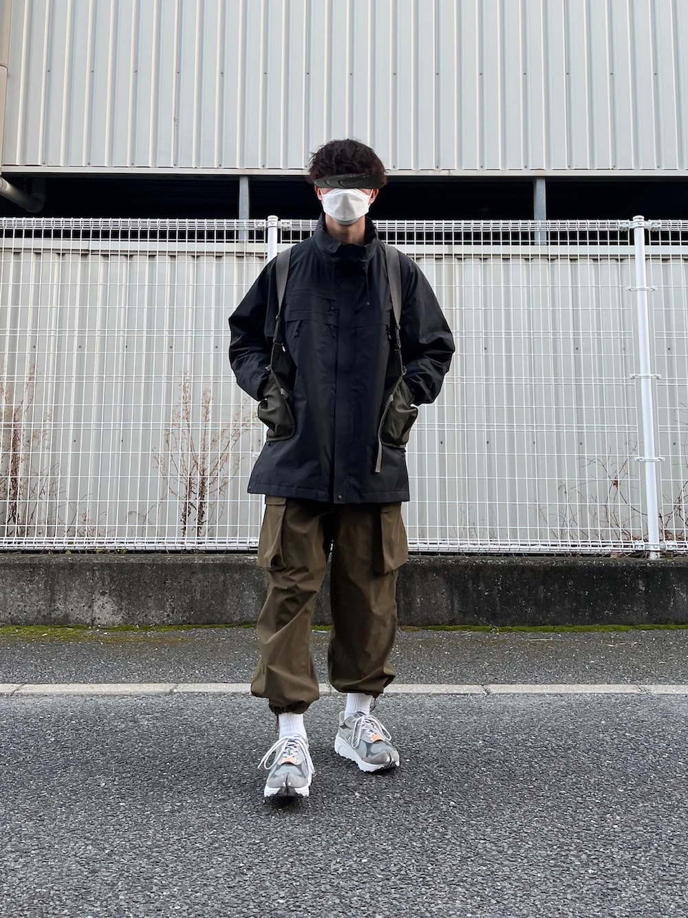 グレー系のスニーカー、グリーン系のその他パンツ、ブラック系のマウンテンパーカーを着用したメンズの冬コーディネートの2枚目の写真
