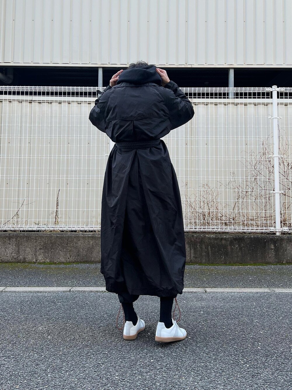 ホワイト系のスニーカー、ブラック系のその他パンツ、ブラック系のトレンチコートを着用したメンズの冬コーディネートの5枚目の写真
