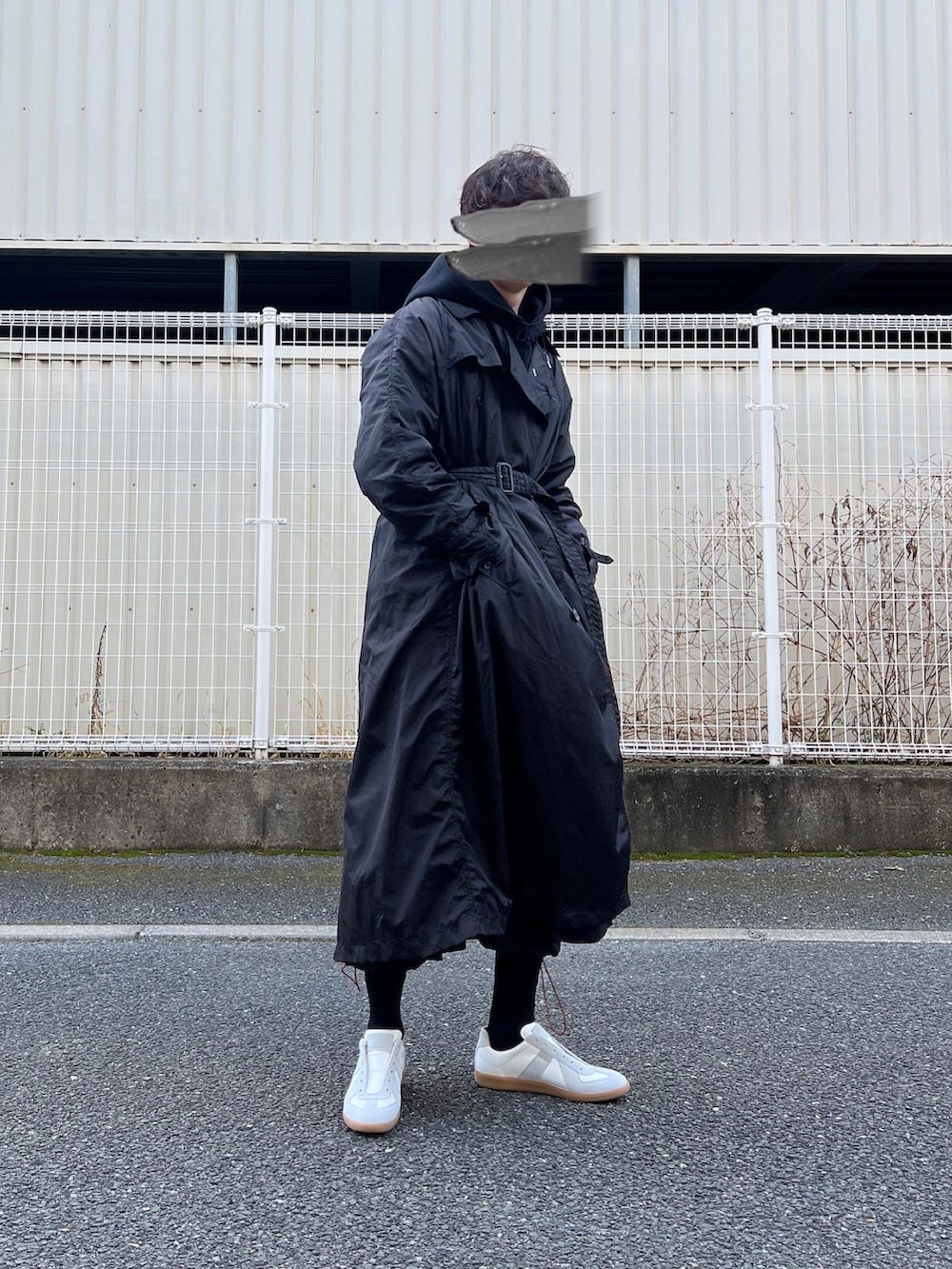 ホワイト系のスニーカー、ブラック系のその他パンツ、ブラック系のトレンチコートを着用したメンズの冬コーディネートの3枚目の写真