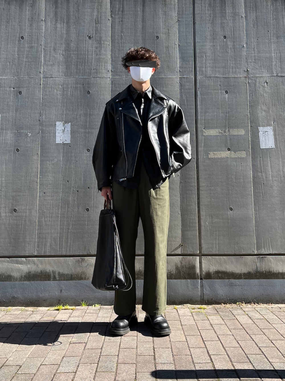 ブラック系のブーツ、ブラック系のトートバッグ、グリーン系のチノパンツを着用したメンズの冬コーディネートの2枚目の写真