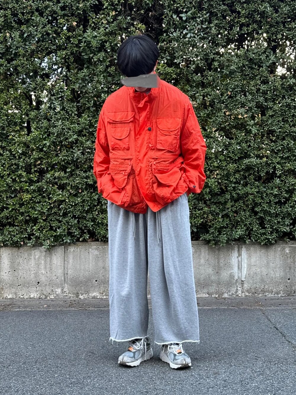 グレー系のスニーカー、グレー系のスウェットパンツ、オレンジ系のナイロンジャケットを着用したメンズの春コーディネートの2枚目の写真