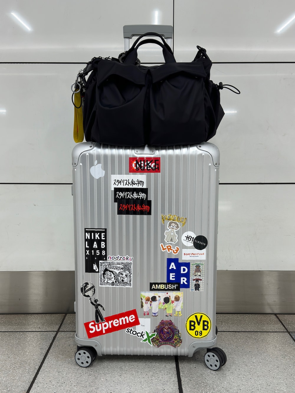 ブラック系のスニーカー、ブラック系のスラックス、シルバー系のスーツケース/キャリーバッグを着用したメンズの秋コーディネートの5枚目の写真