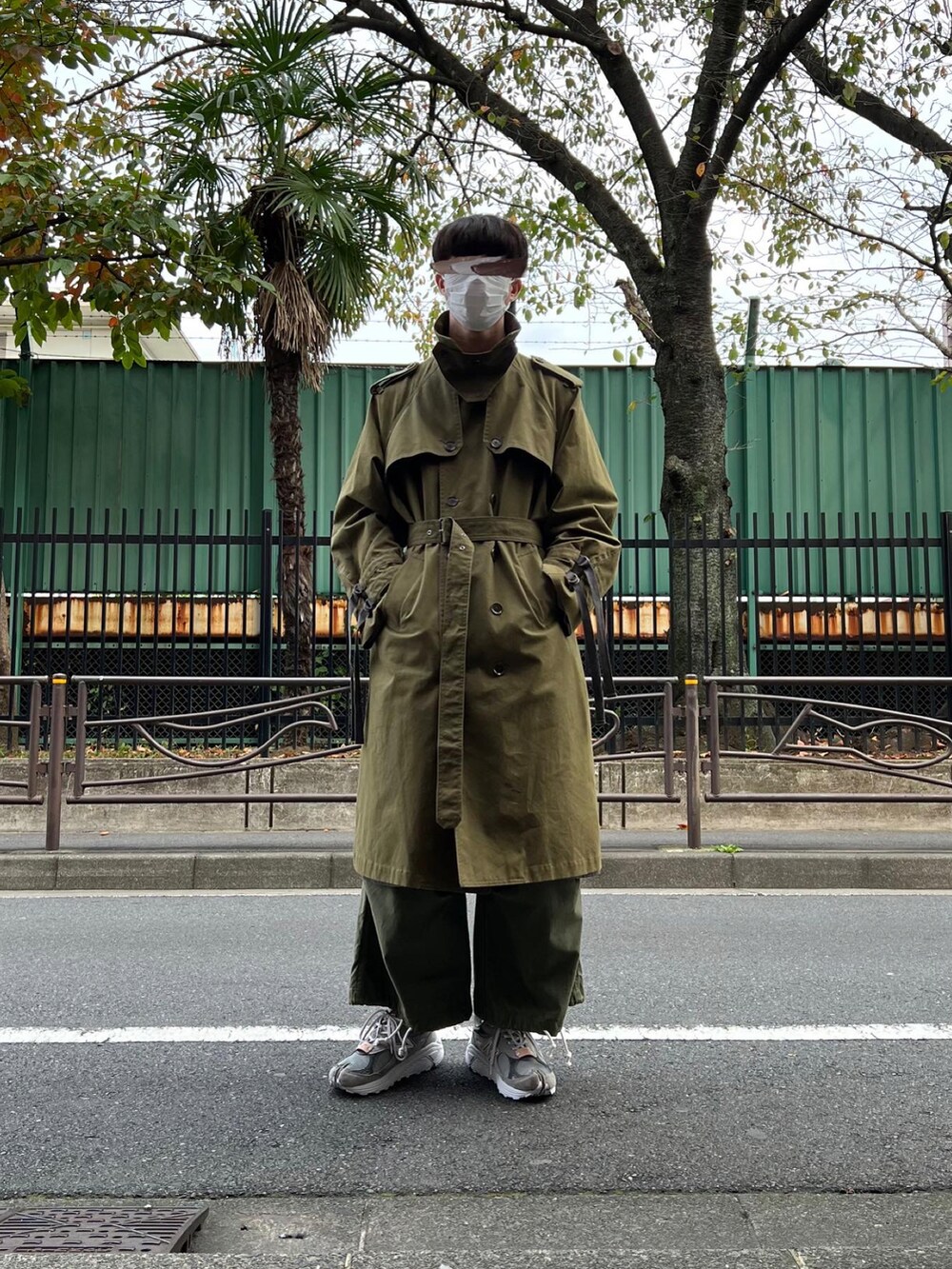 グレー系のスニーカー、グリーン系のカーゴパンツ、グリーン系のトレンチコートを着用したメンズの冬コーディネートの3枚目の写真