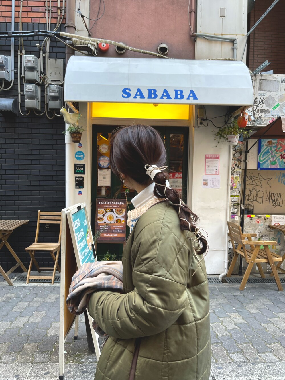 ベージュ系のニット/セーター、グリーン系のノーカラーコート、ホワイト系のスカートを着用したレディースの冬コーディネートの2枚目の写真