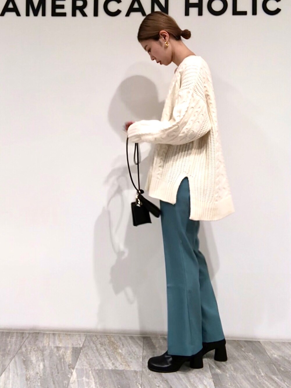 ブルー系のその他パンツ、ホワイト系のニット/セーター、ブラック系のショルダーバッグを着用したレディースの冬コーディネートの2枚目の写真