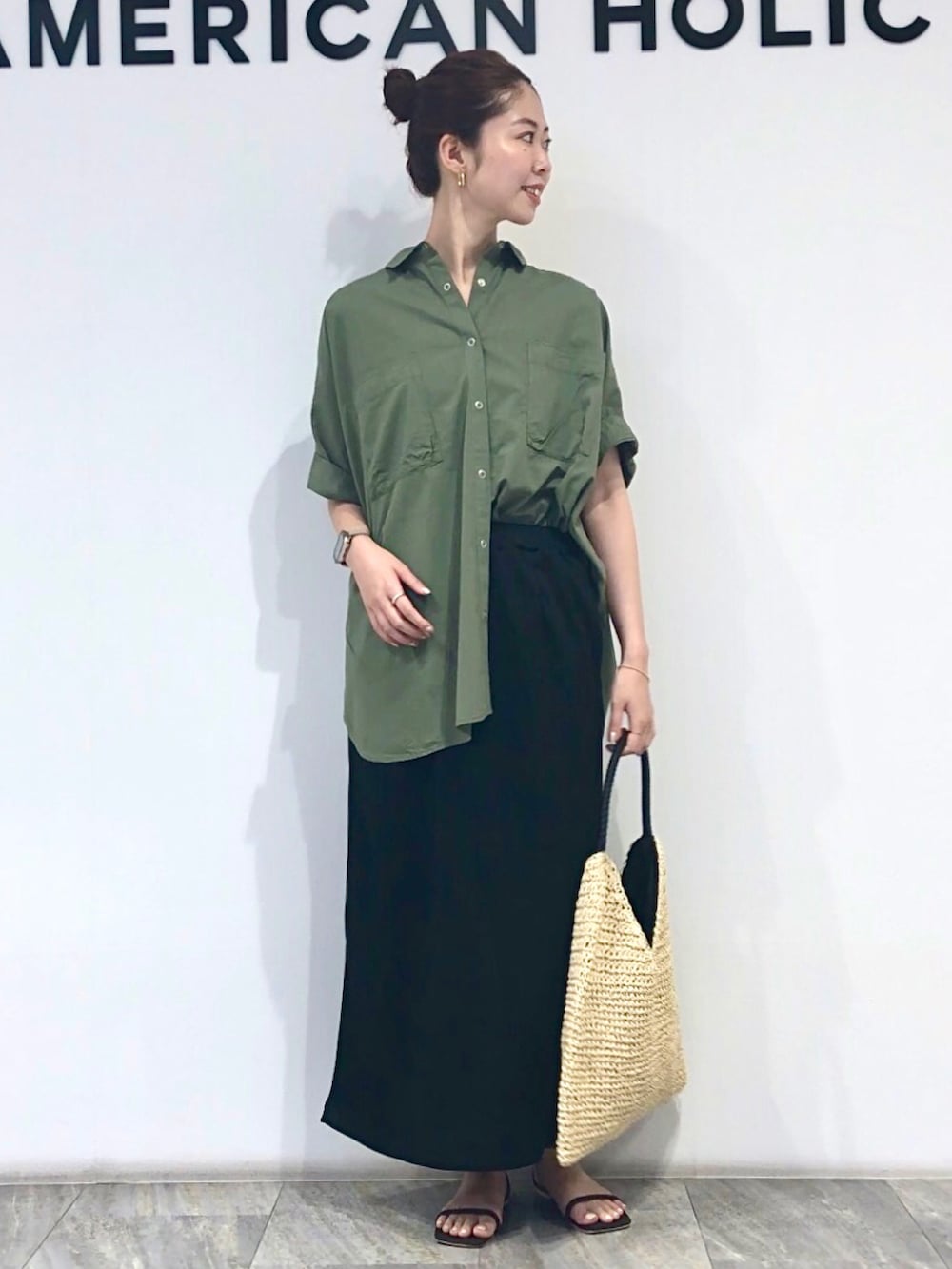 ブラック系のスカート、ベージュ系のトートバッグ、グリーン系のシャツ/ブラウスを着用したレディースの夏コーディネートの2枚目の写真
