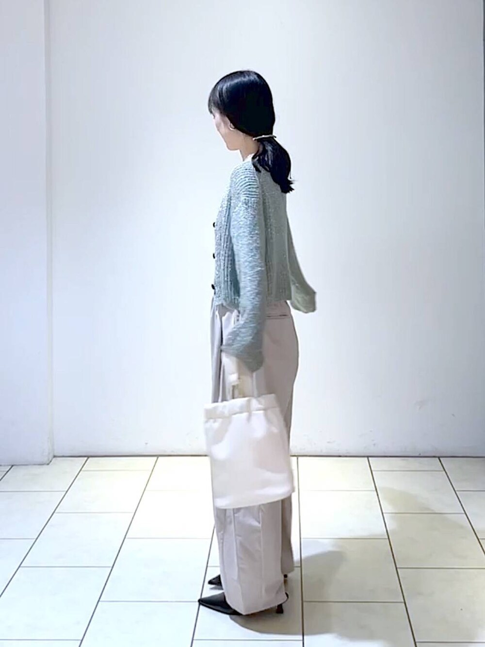 グレー系のカーディガン/ボレロ、ブラック系のパンプス、ホワイト系のショルダーバッグを着用したレディースの秋コーディネートの4枚目の写真