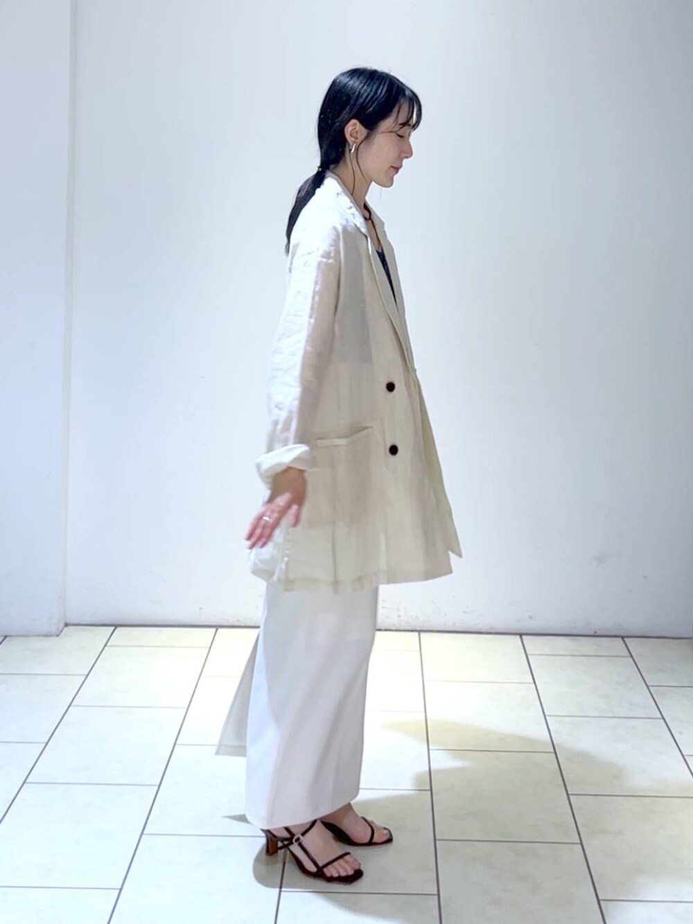 ブラック系のタンクトップ、ホワイト系のスカート、ベージュ系のテーラードジャケットを着用したレディースの夏コーディネートの3枚目の写真