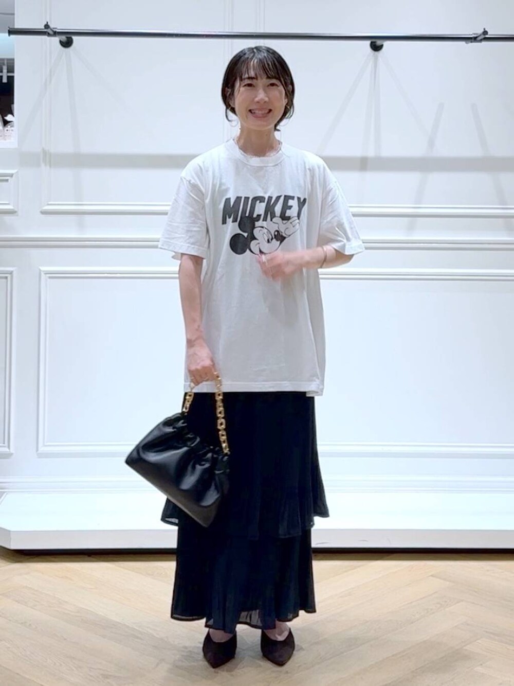 ブラック系のスカート、ホワイト系のTシャツ/カットソー、ブラウン系のパンプスを着用したレディースの秋コーディネートの6枚目の写真