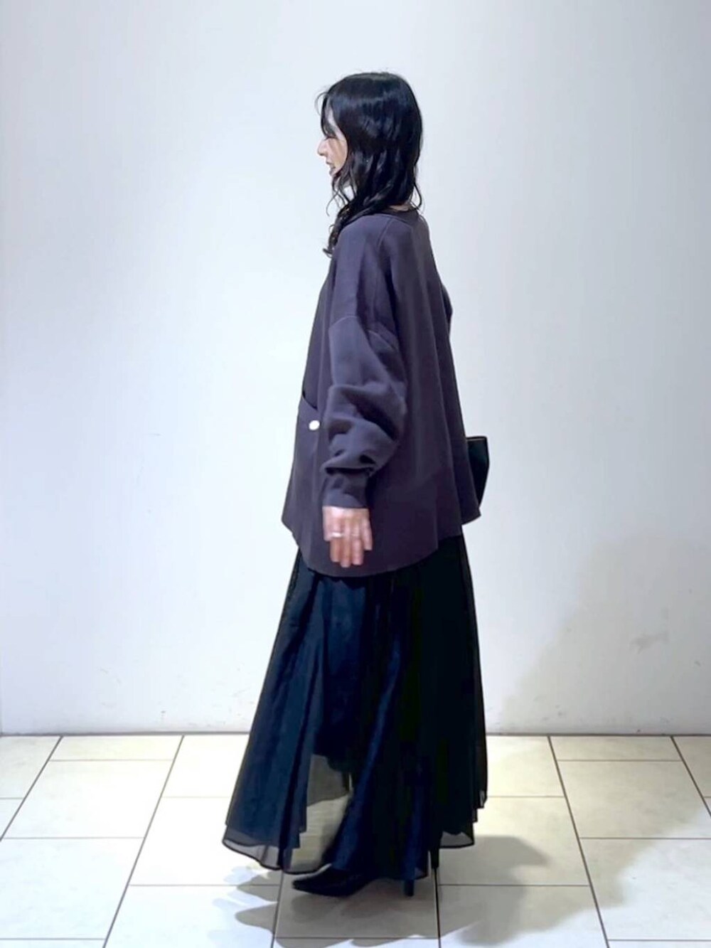 ブラック系のショルダーバッグ、ブラック系のスカート、ブラック系のパンプスを着用したレディースの春コーディネートの5枚目の写真