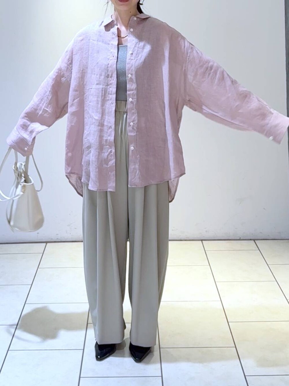 グレー系のタンクトップ、ホワイト系のショルダーバッグ、ブラック系のパンプスを着用したレディースの春コーディネートの2枚目の写真