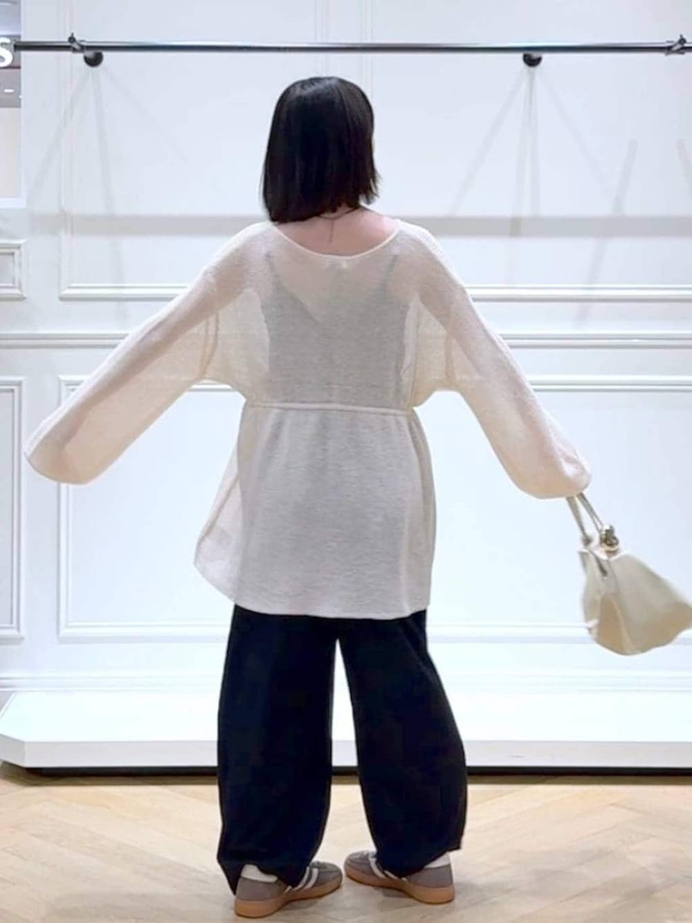 ブラック系のスラックス、ホワイト系のカーディガン/ボレロ、その他のネックレスを着用したレディースの春コーディネートの4枚目の写真