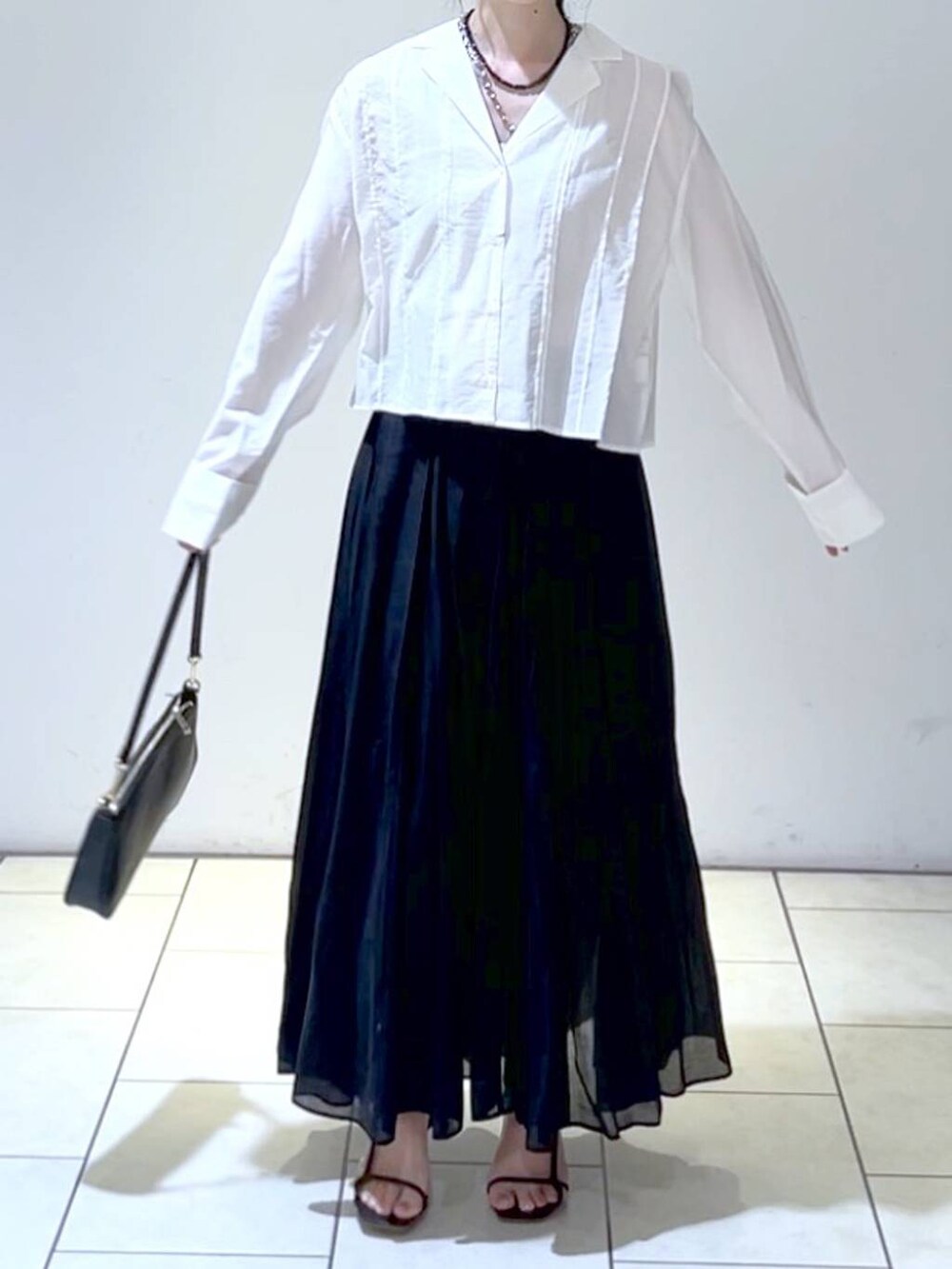 ブラック系のショルダーバッグ、ブラック系のスカート、ホワイト系のシャツ/ブラウスを着用したレディースの春コーディネートの2枚目の写真