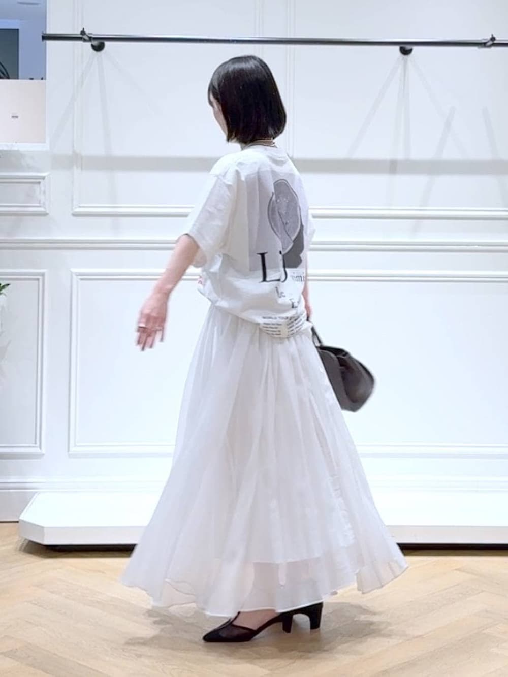 ホワイト系のスカート、ブラック系のパンプス、ブラウン系のショルダーバッグを着用したレディースの春コーディネートの5枚目の写真