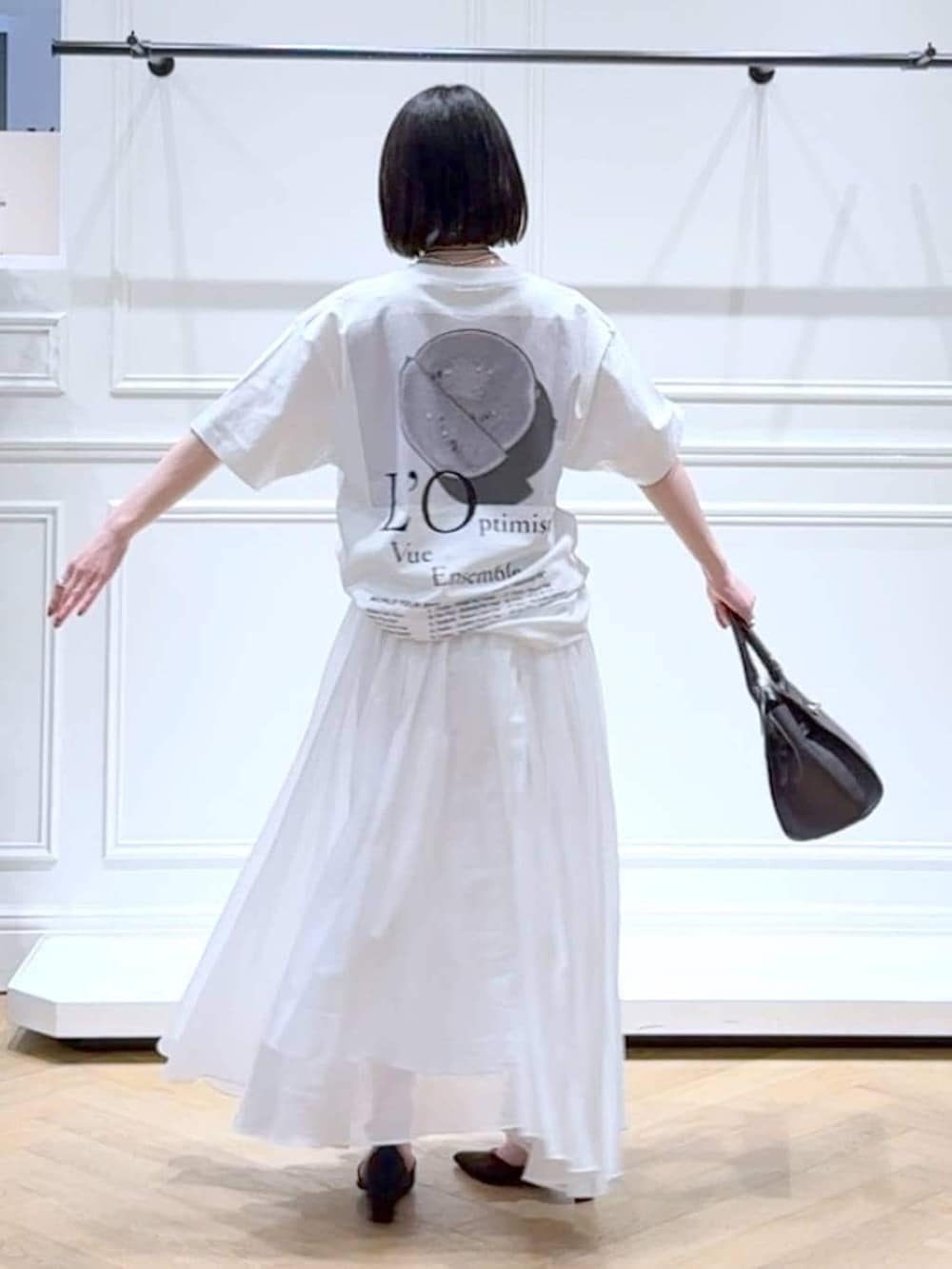 ホワイト系のスカート、ブラック系のパンプス、ブラウン系のショルダーバッグを着用したレディースの春コーディネートの4枚目の写真