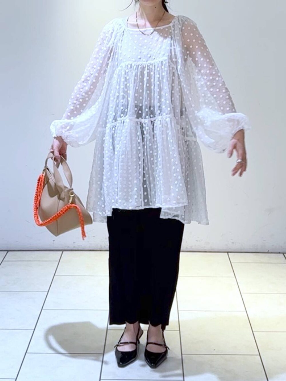 ブラック系のパンプス、ブラック系のスカート、ホワイト系のワンピースを着用したレディースの春コーディネートの2枚目の写真