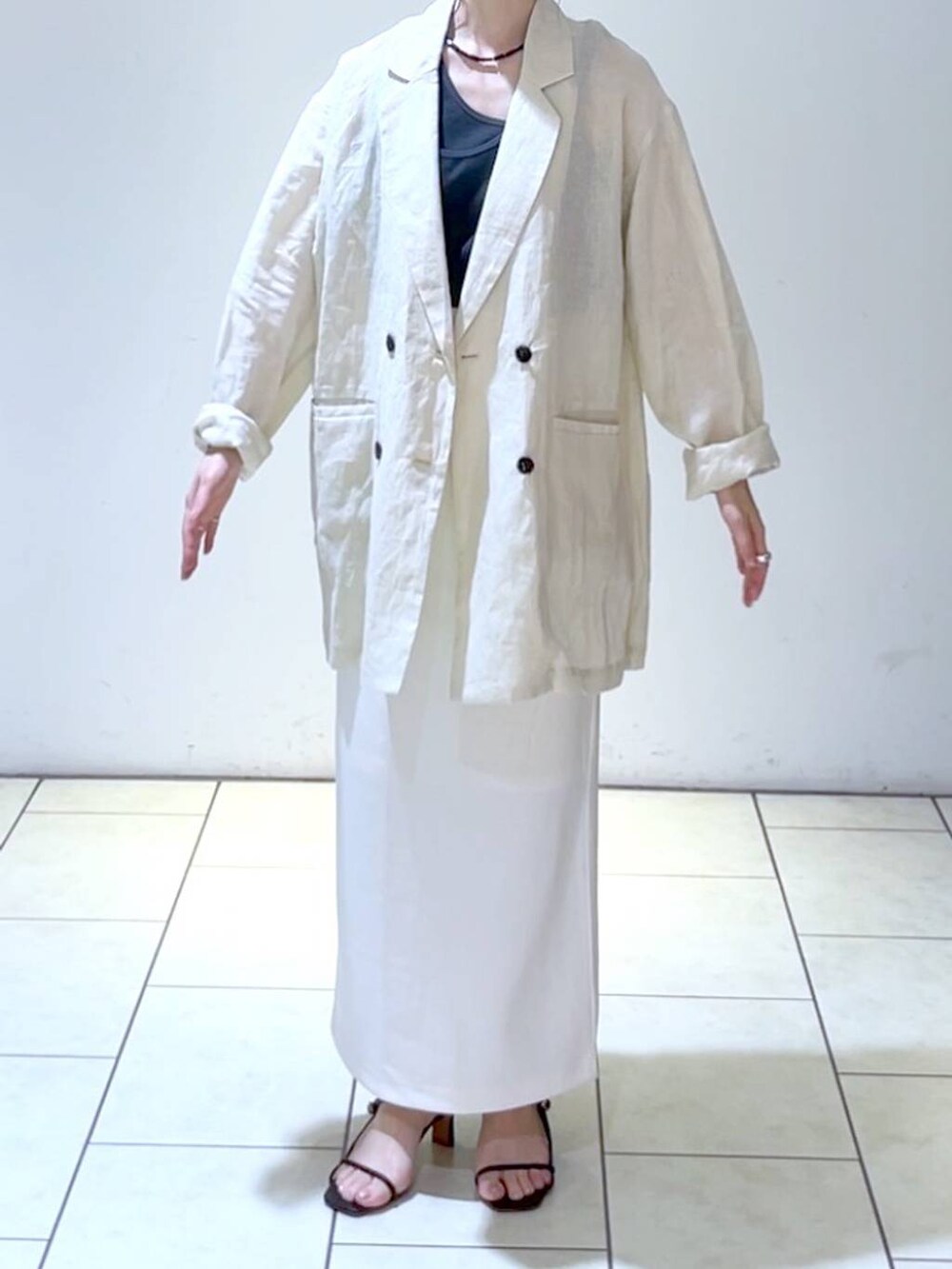 ブラック系のタンクトップ、ホワイト系のスカート、ベージュ系のテーラードジャケットを着用したレディースの夏コーディネートの2枚目の写真