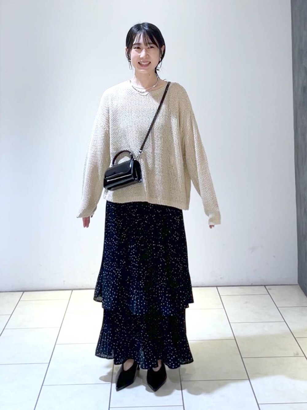 ベージュ系のニット/セーター、ブラック系のパンプス、グレー系のスカートを着用したレディースの秋コーディネートの2枚目の写真