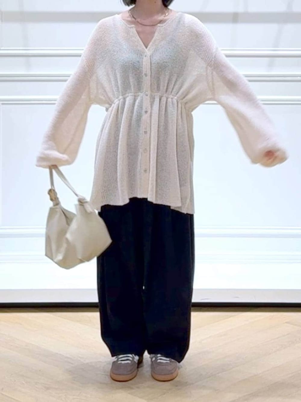 ブラック系のスラックス、ホワイト系のカーディガン/ボレロ、その他のネックレスを着用したレディースの春コーディネートの2枚目の写真