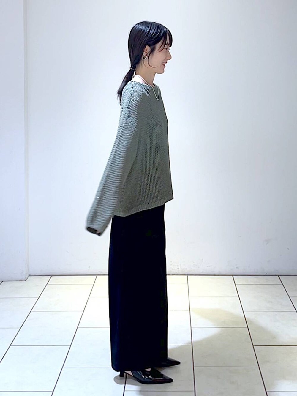 グリーン系のニット/セーター、ブラック系のパンプス、ブラック系のスカートを着用したレディースの秋コーディネートの3枚目の写真