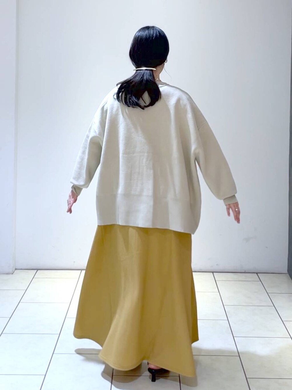 ブラック系のサンダル、オレンジ系のワンピース、ベージュ系のカーディガン/ボレロを着用したレディースの春コーディネートの4枚目の写真