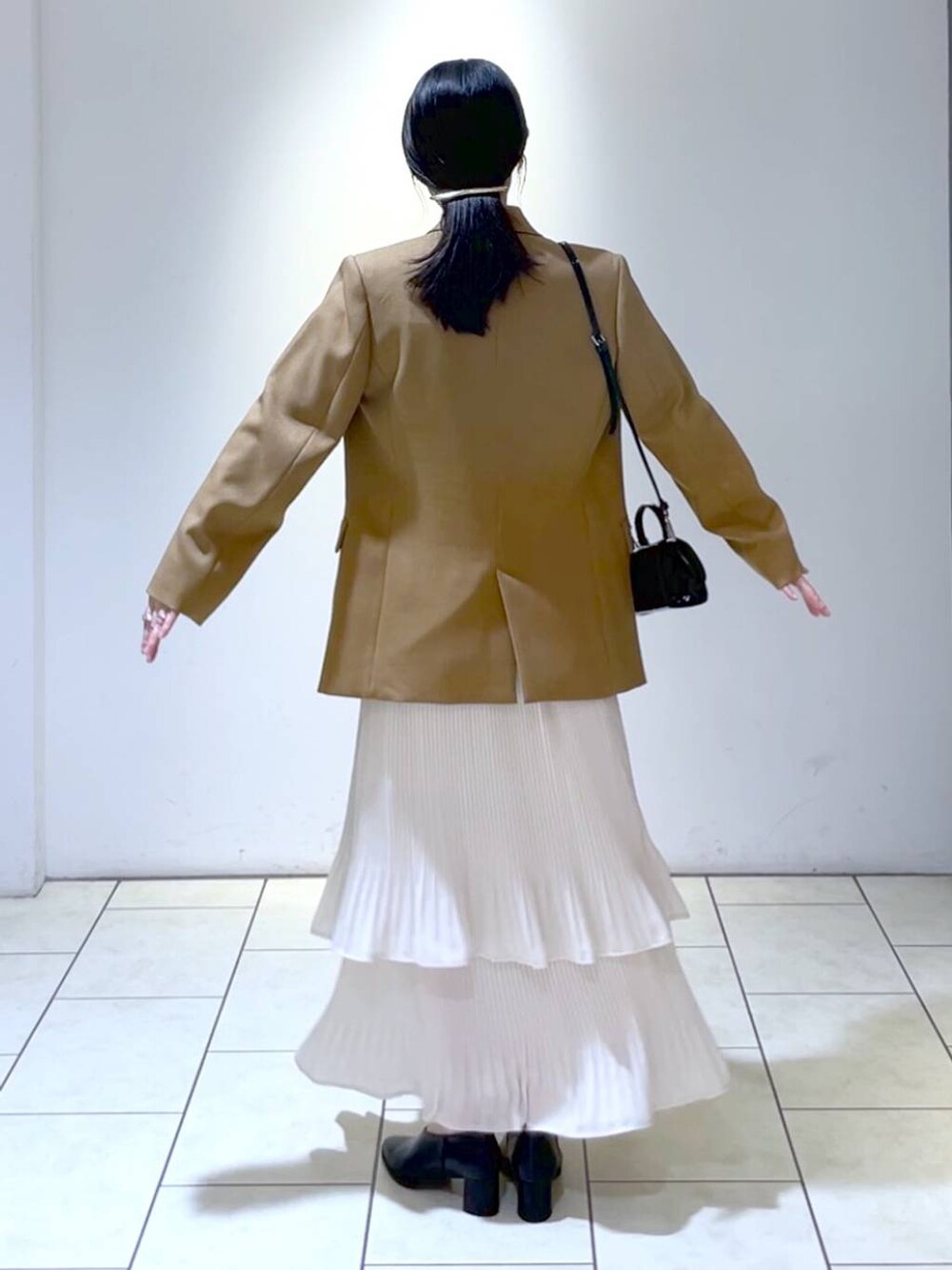 イエロー系のテーラードジャケット、ホワイト系のニット/セーター、ホワイト系のスカートを着用したレディースの秋コーディネートの4枚目の写真
