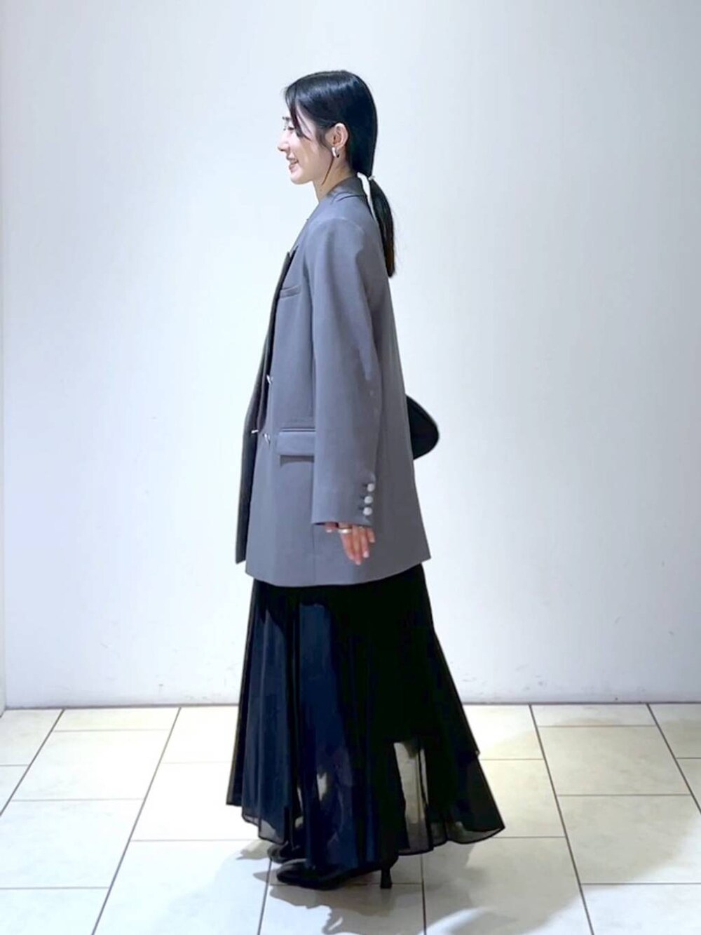 ブルー系のニット/セーター、ブラック系のショルダーバッグ、ブラック系のスカートを着用したレディースの春コーディネートの5枚目の写真