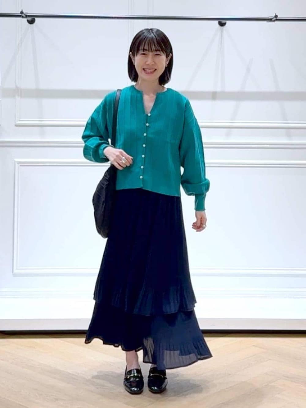 ブルー系のスカート、グリーン系のカーディガン/ボレロ、ブラック系のローファーを着用したレディースの春コーディネートの6枚目の写真