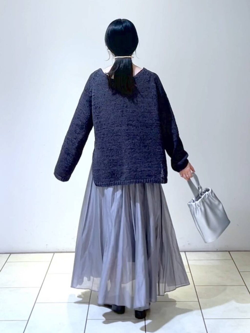 ブラック系のローファー、グレー系のスカート、シルバー系のショルダーバッグを着用したレディースの春コーディネートの4枚目の写真