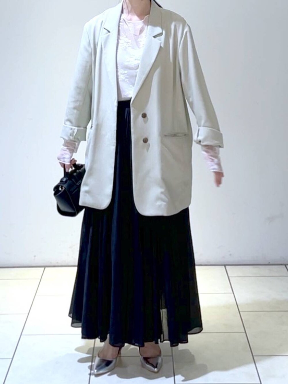 ホワイト系のTシャツ/カットソー、シルバー系のサンダル、ブラック系のスカートを着用したレディースの春コーディネートの2枚目の写真