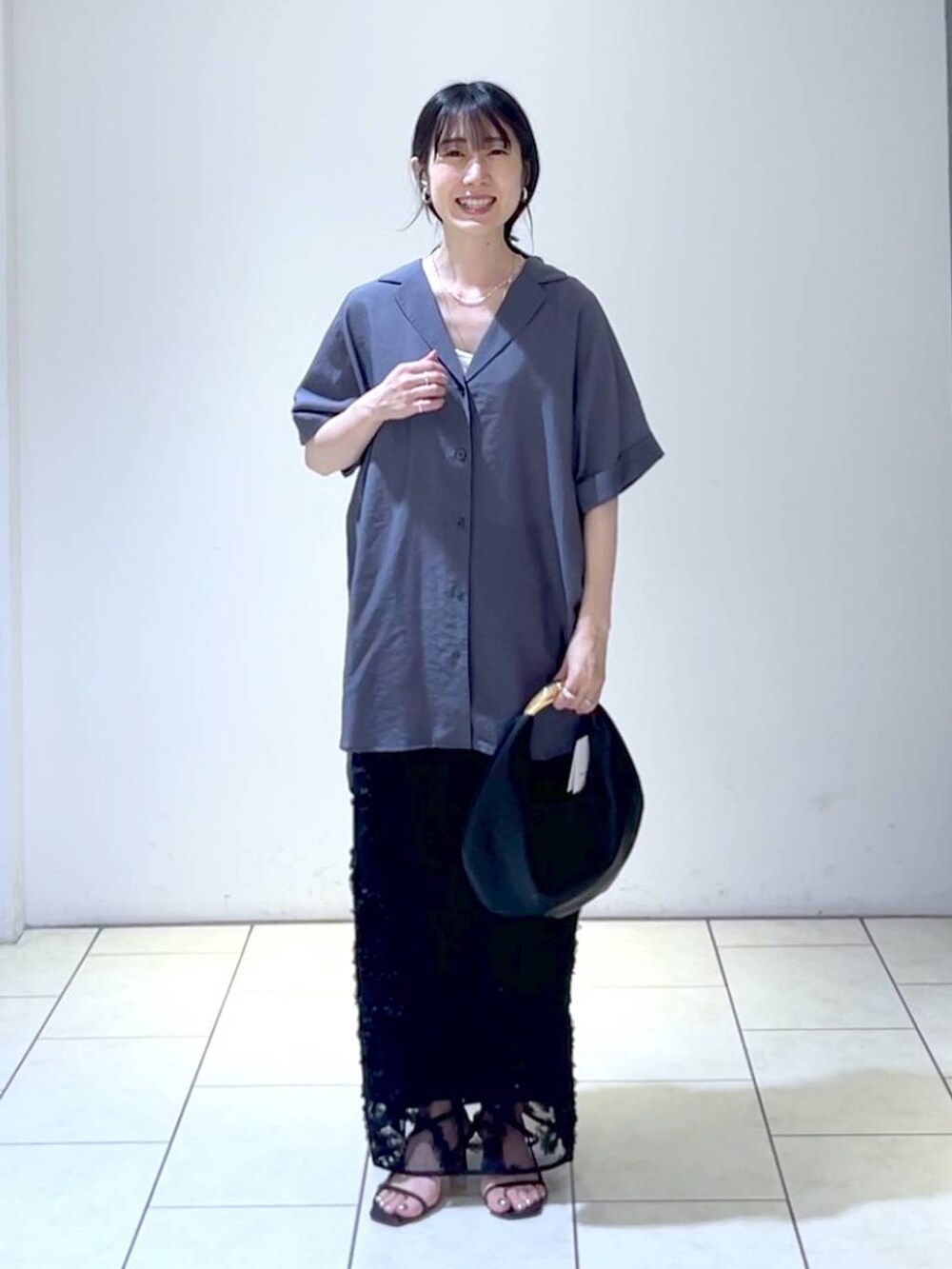 ブラック系のハンドバッグ、グレー系のシャツ/ブラウス、ブラック系のスカートを着用したレディースの夏コーディネートの6枚目の写真