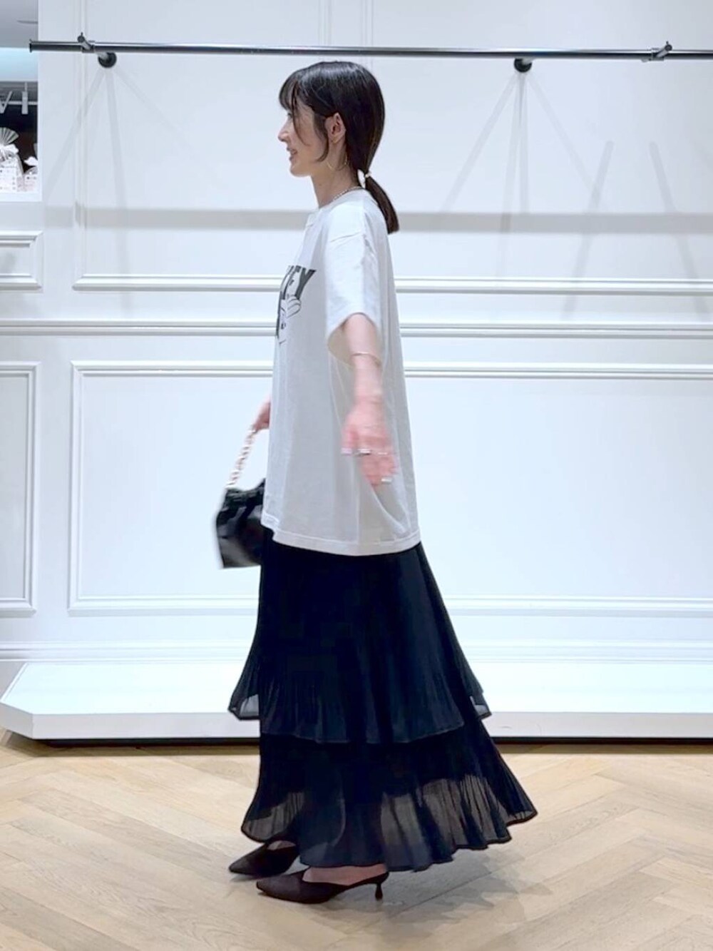 ブラック系のスカート、ホワイト系のTシャツ/カットソー、ブラウン系のパンプスを着用したレディースの秋コーディネートの5枚目の写真