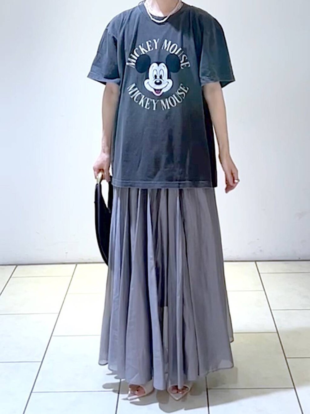 ホワイト系のサンダル、ブラック系のハンドバッグ、グレー系のスカートを着用したレディースの夏コーディネートの2枚目の写真