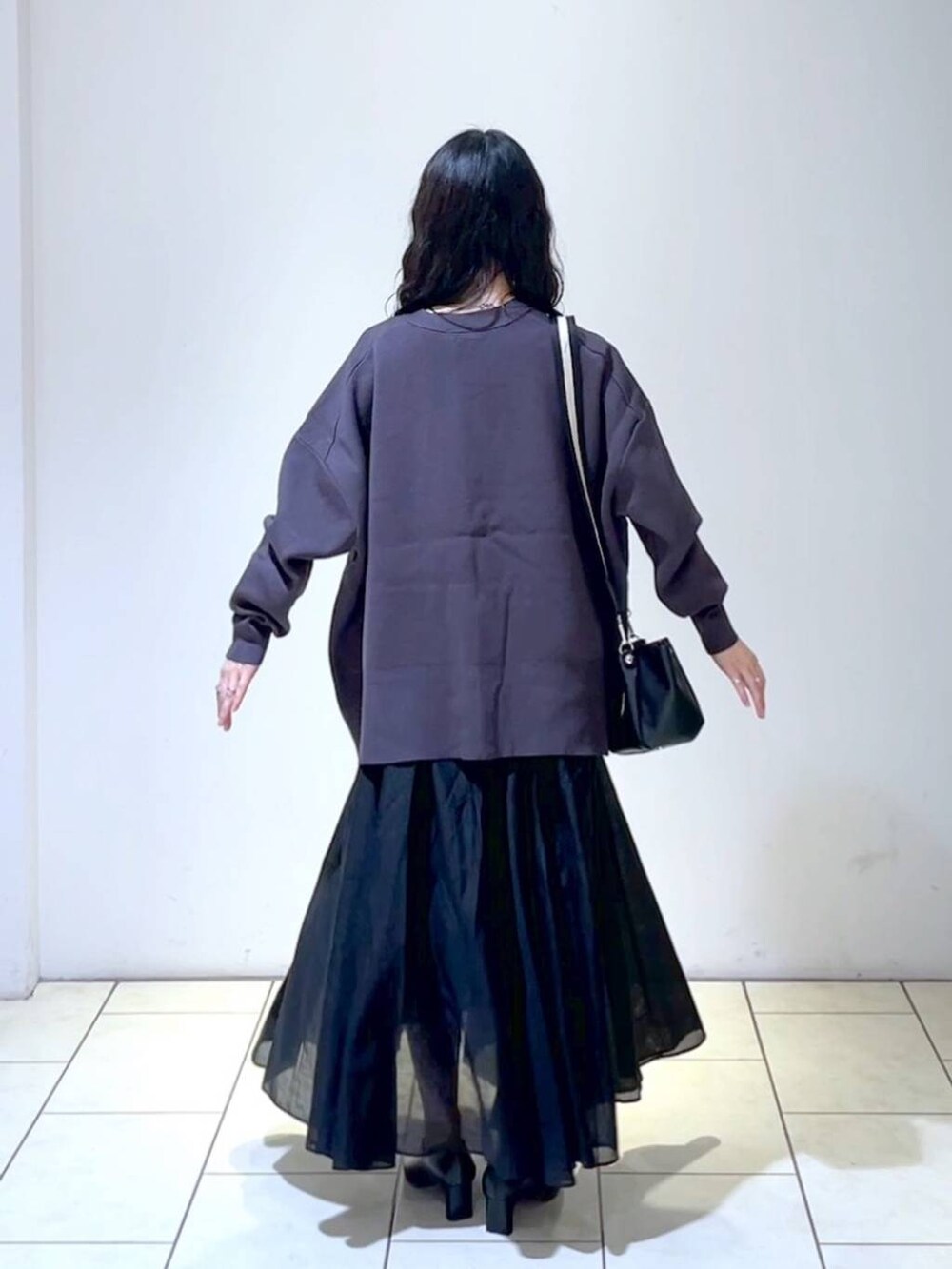 ブラック系のショルダーバッグ、ブラック系のスカート、ブラック系のパンプスを着用したレディースの春コーディネートの4枚目の写真