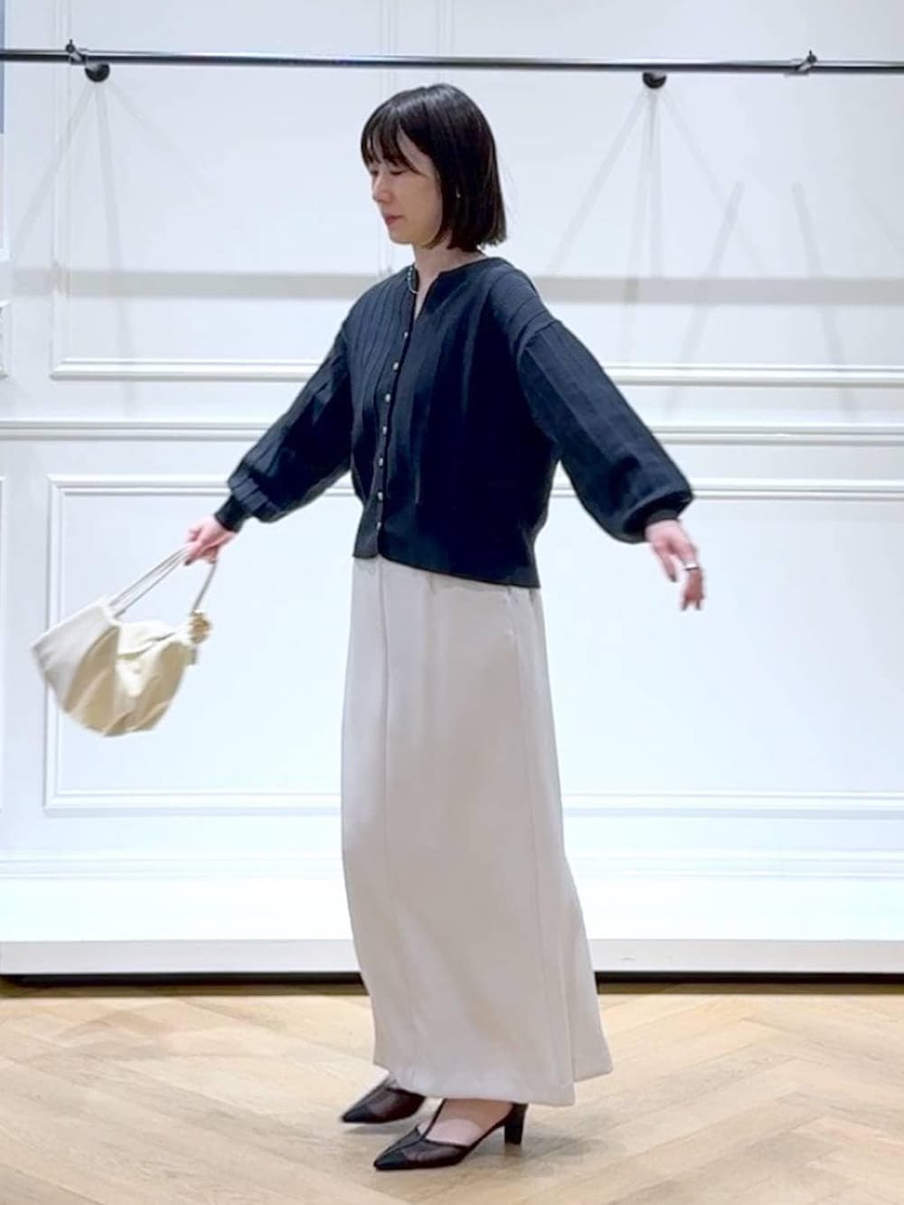 ブルー系のカーディガン/ボレロ、ブラック系のパンプス、ホワイト系のスカートを着用したレディースの春コーディネートの5枚目の写真