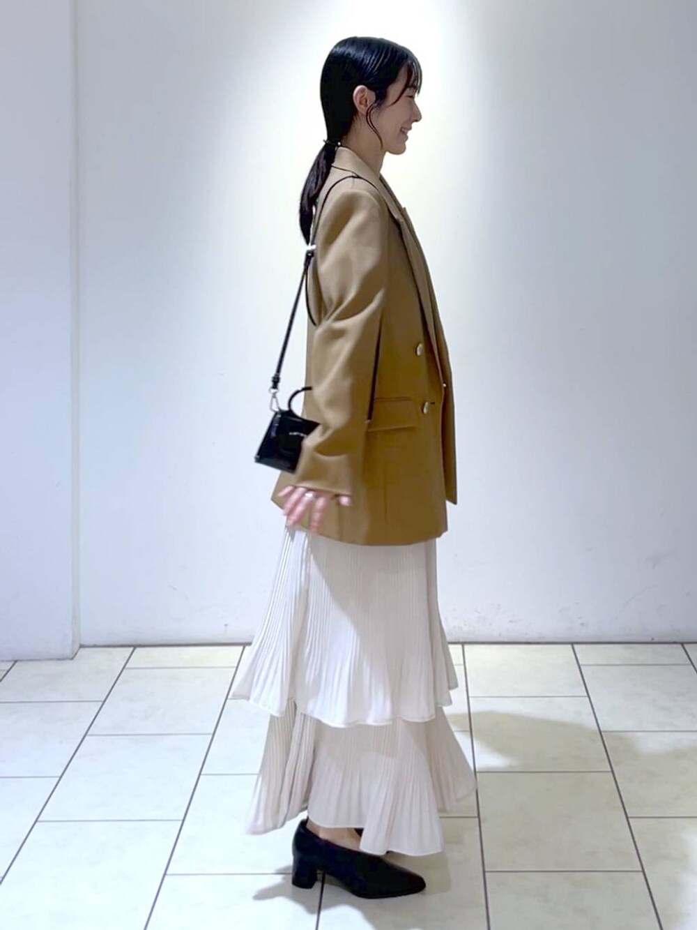 イエロー系のテーラードジャケット、ホワイト系のニット/セーター、ホワイト系のスカートを着用したレディースの秋コーディネートの3枚目の写真
