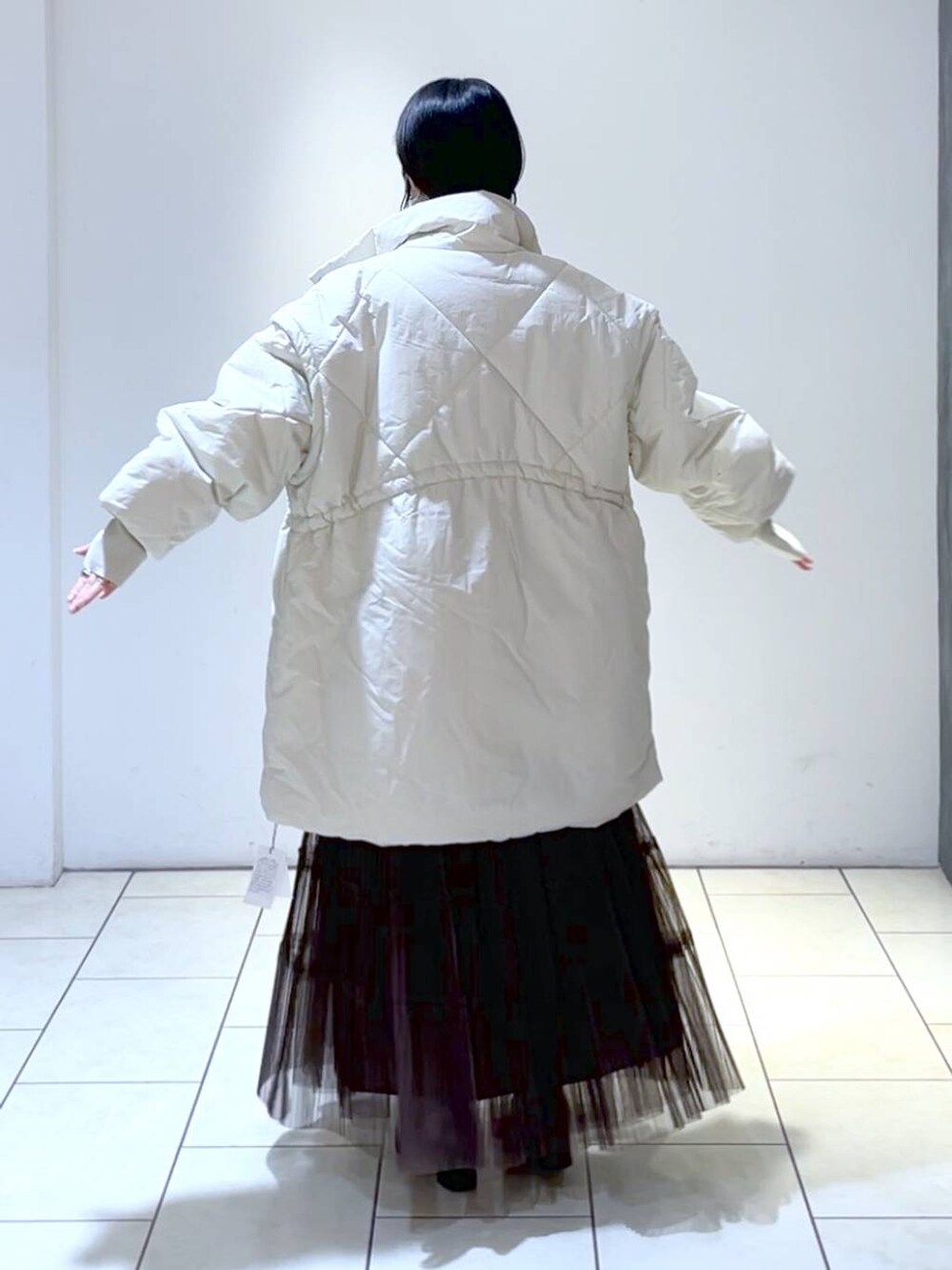 ピンク系のニット/セーター、ホワイト系のダウンジャケット/コート、ブラウン系のスカートを着用したレディースの冬コーディネートの3枚目の写真