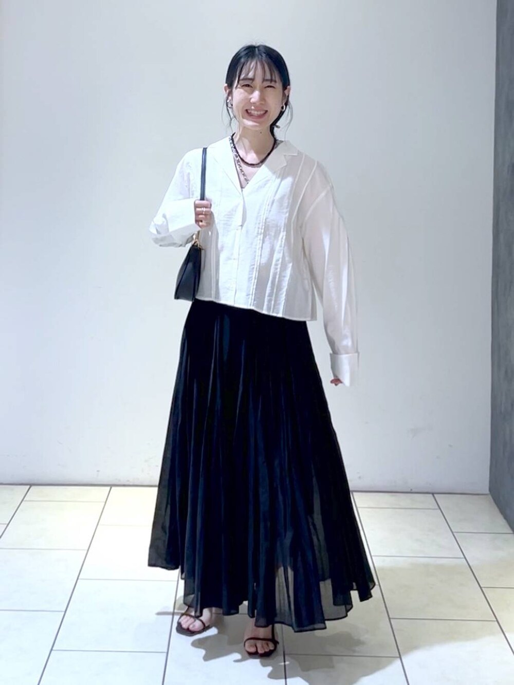 ブラック系のショルダーバッグ、ブラック系のスカート、ホワイト系のシャツ/ブラウスを着用したレディースの春コーディネートの6枚目の写真