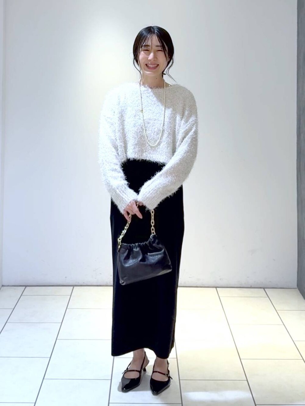ホワイト系のワンピース、ブラック系のパンプス、グレー系のテーラードジャケットを着用したレディースの冬コーディネートの2枚目の写真