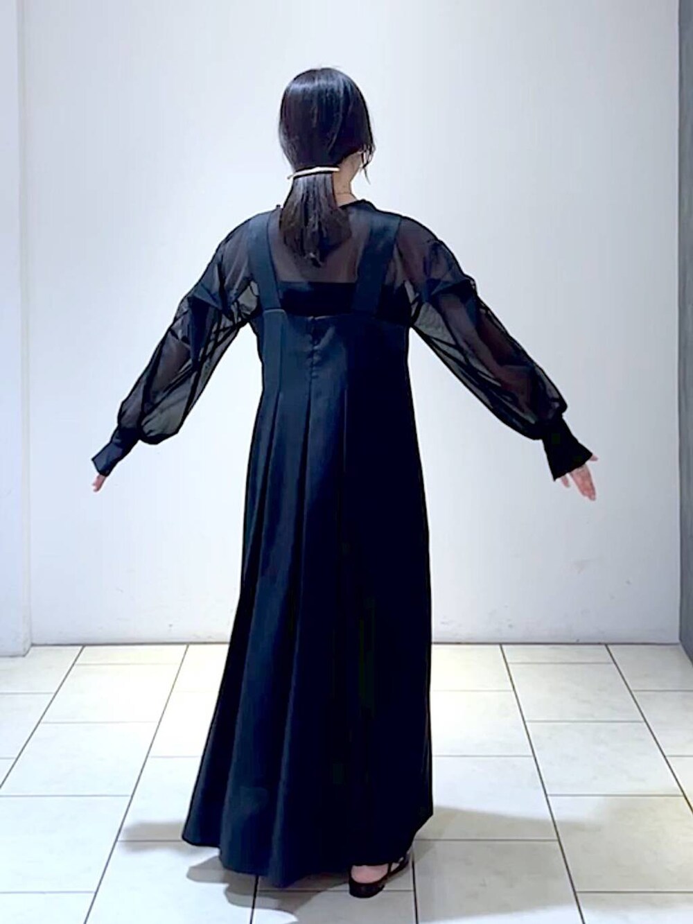 ブラック系のジャンパースカート、ブラック系のシャツ/ブラウス、ブラック系のパンプスを着用したレディースの秋コーディネートの4枚目の写真