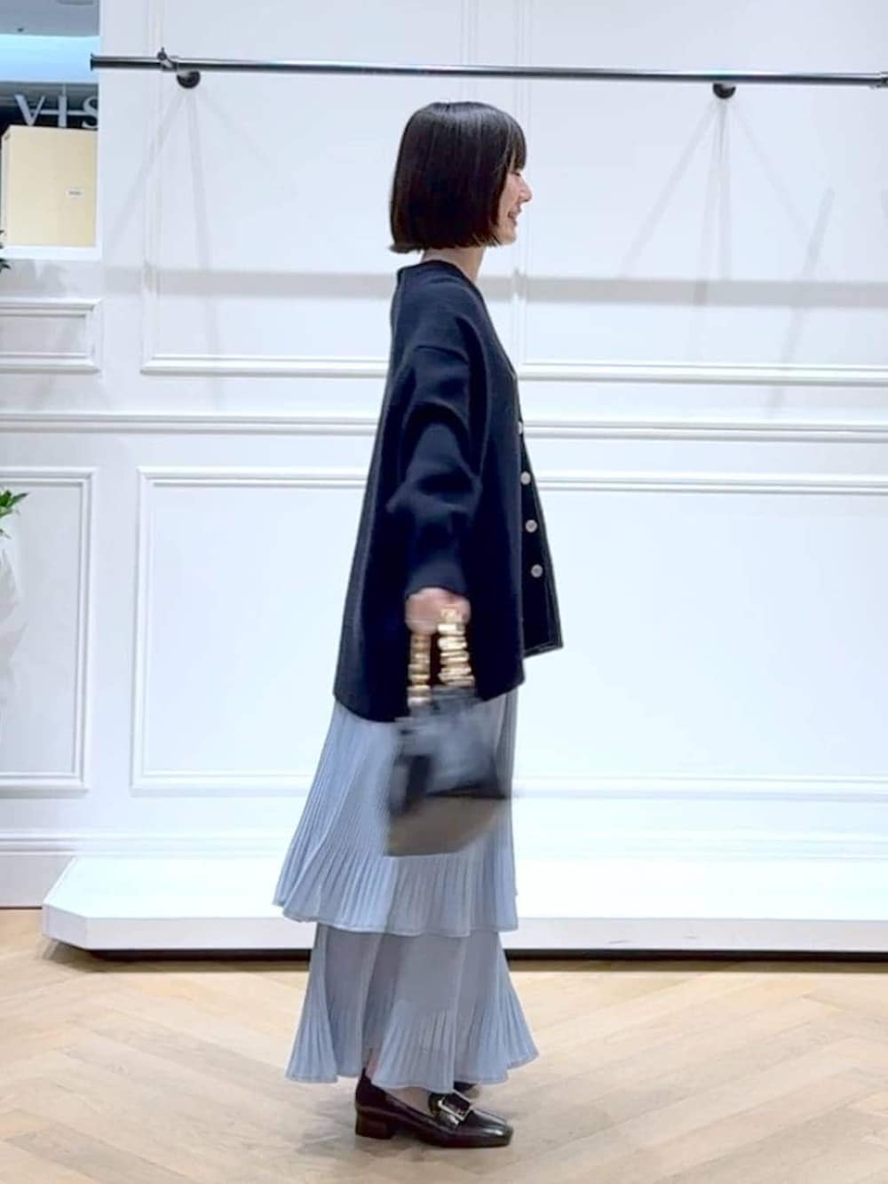 ブルー系のスカート、ブルー系のカーディガン/ボレロ、ブラック系のショルダーバッグを着用したレディースの春コーディネートの3枚目の写真