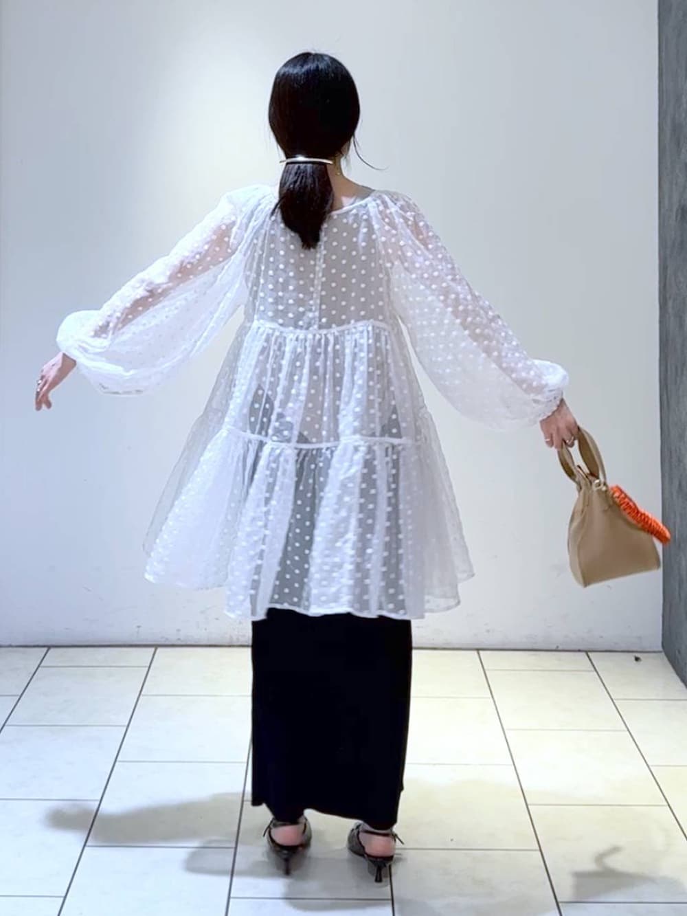 ブラック系のパンプス、ブラック系のスカート、ホワイト系のワンピースを着用したレディースの春コーディネートの4枚目の写真