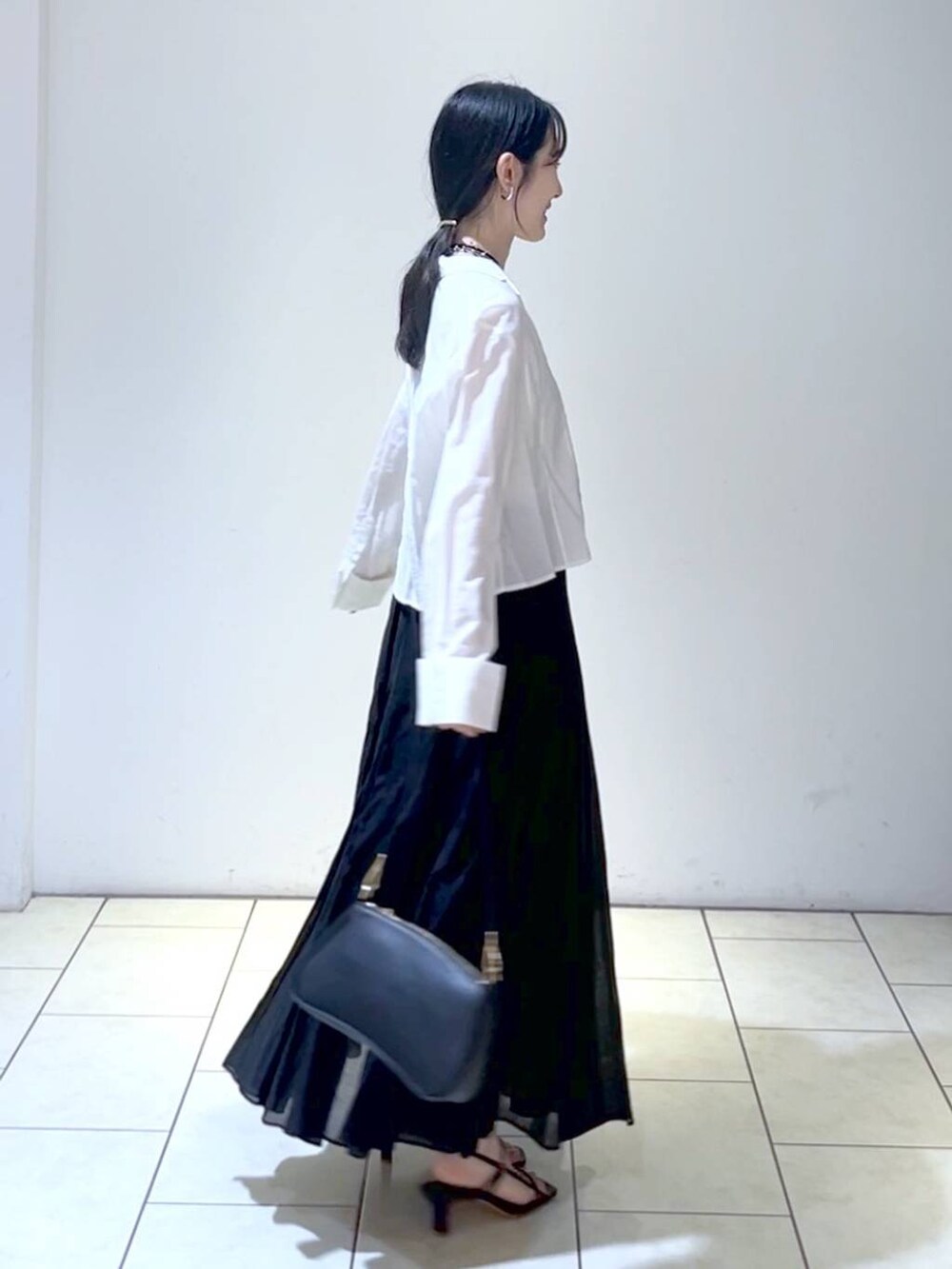 ブラック系のショルダーバッグ、ブラック系のスカート、ホワイト系のシャツ/ブラウスを着用したレディースの春コーディネートの3枚目の写真