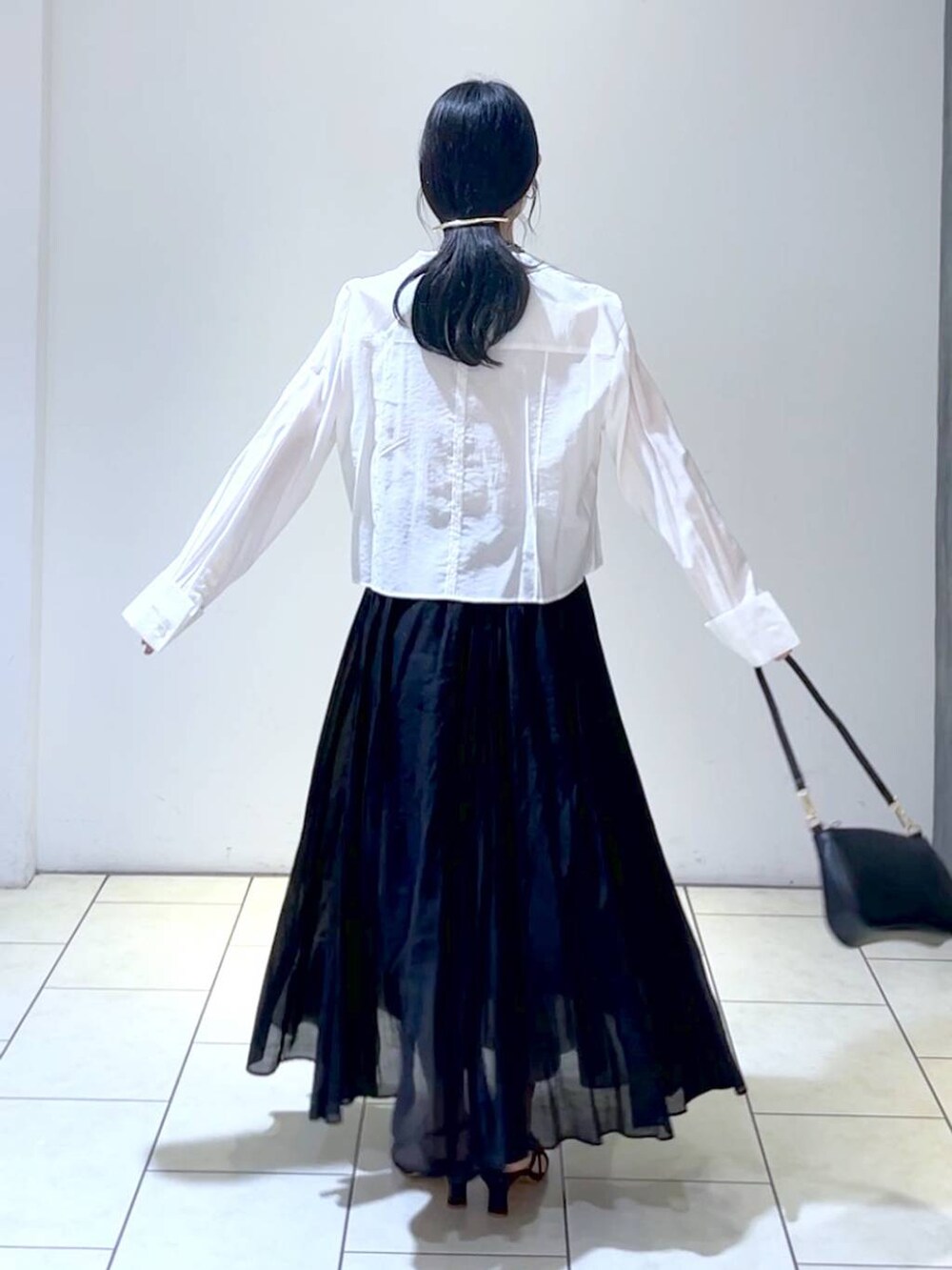 ブラック系のショルダーバッグ、ブラック系のスカート、ホワイト系のシャツ/ブラウスを着用したレディースの春コーディネートの4枚目の写真