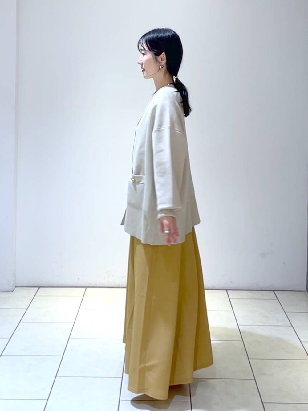 ブラック系のサンダル、オレンジ系のワンピース、ベージュ系のカーディガン/ボレロを着用したレディースの春コーディネートの5枚目の写真