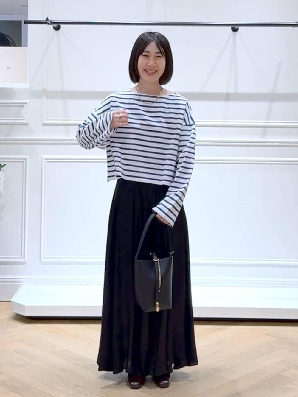 ブラック系のスカート、ブラウン系のローファー、ブラック系のショルダーバッグを着用したレディースの春コーディネートの6枚目の写真