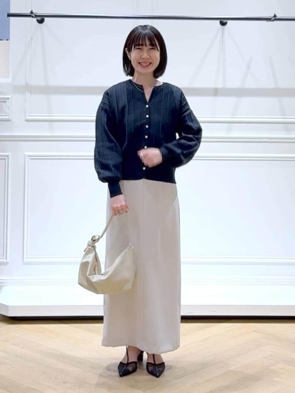 ブルー系のカーディガン/ボレロ、ブラック系のパンプス、ホワイト系のスカートを着用したレディースの春コーディネートの6枚目の写真