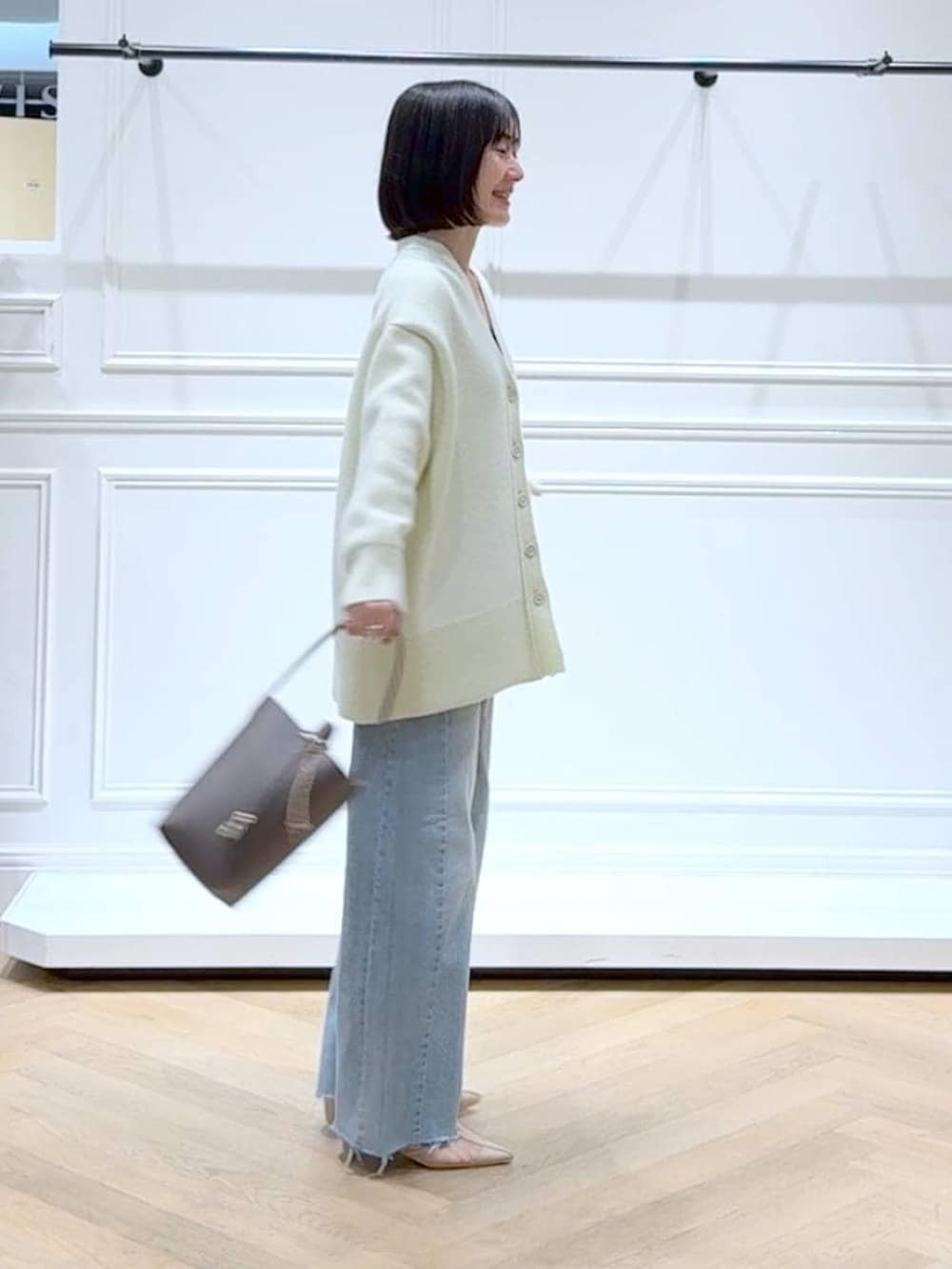 イエロー系のカーディガン/ボレロ、ブルー系のデニムパンツ、ブラウン系のショルダーバッグを着用したレディースの春コーディネートの2枚目の写真