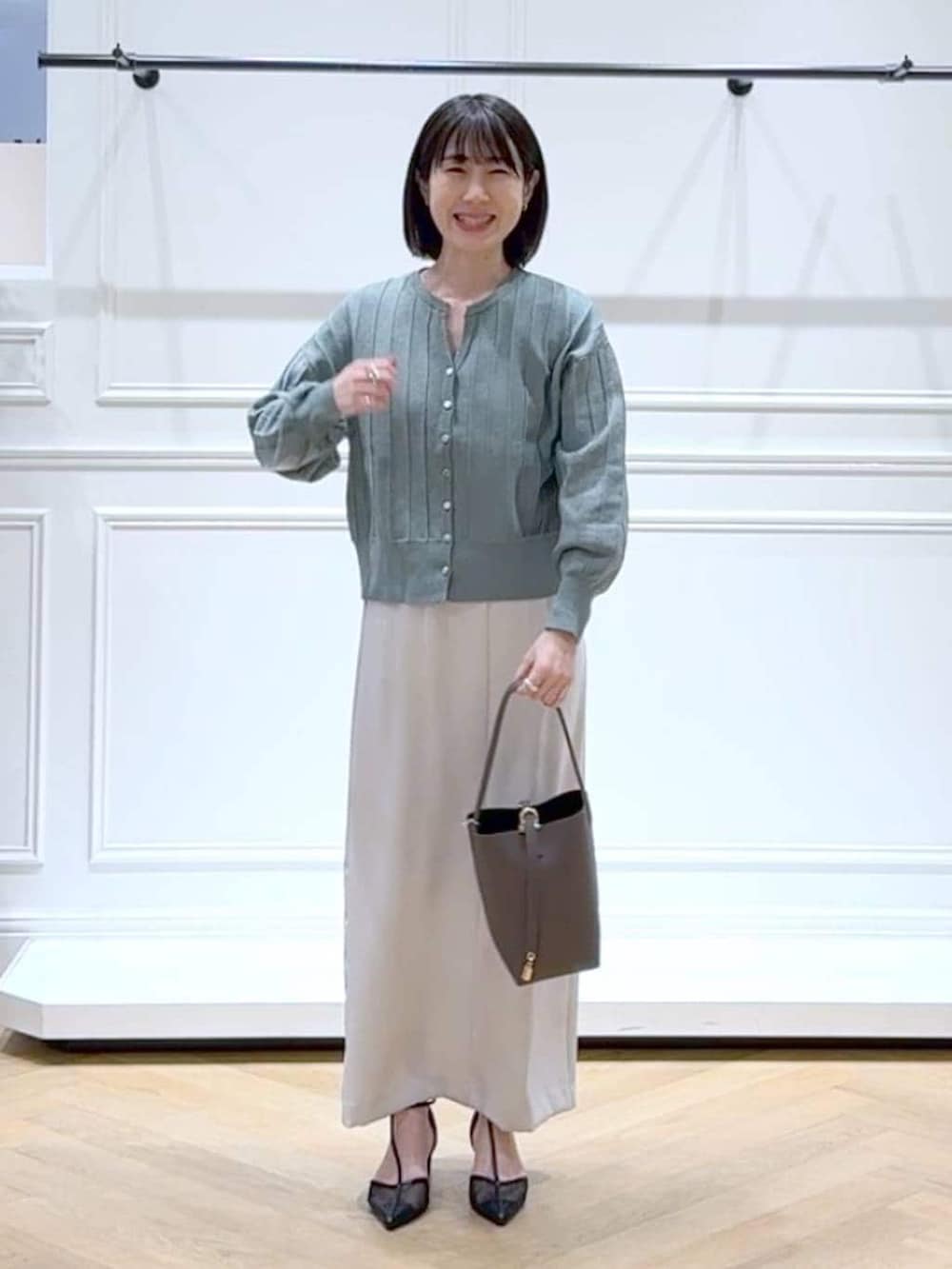 グリーン系のカーディガン/ボレロ、ブラック系のパンプス、ブラウン系のショルダーバッグを着用したレディースの春コーディネートの6枚目の写真