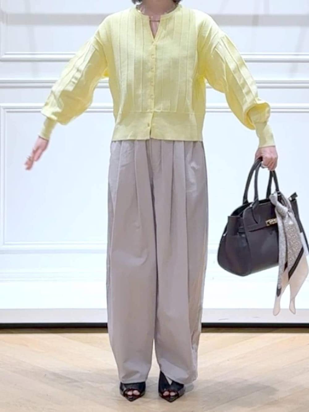 イエロー系のカーディガン/ボレロ、ブラウン系のショルダーバッグ、ブラック系のサンダルを着用したレディースの春コーディネートの2枚目の写真